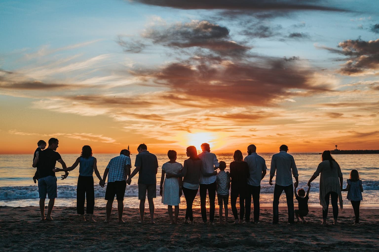 A multigenerational family standing together at sunset