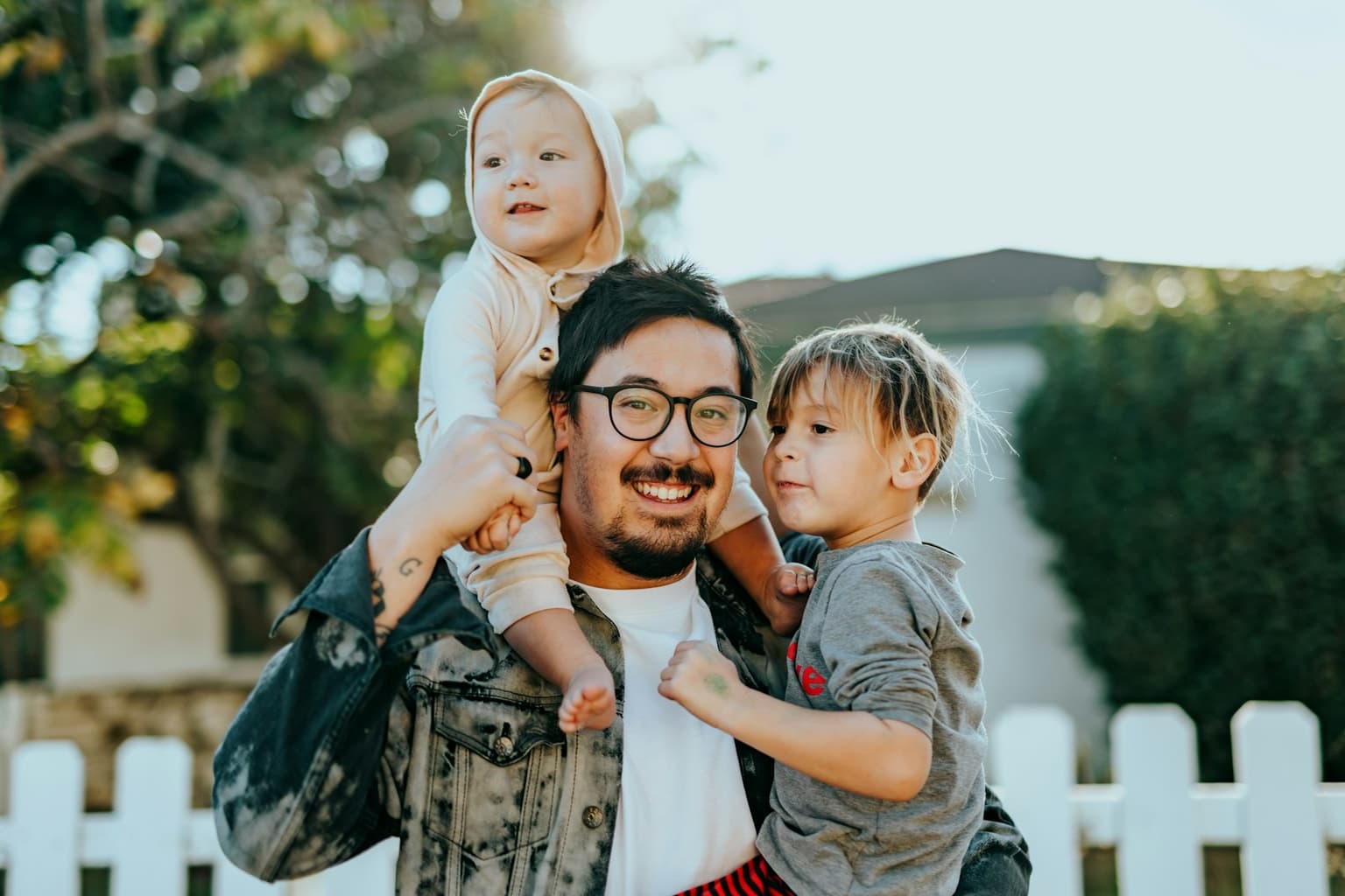 A parent with two young children outside a home